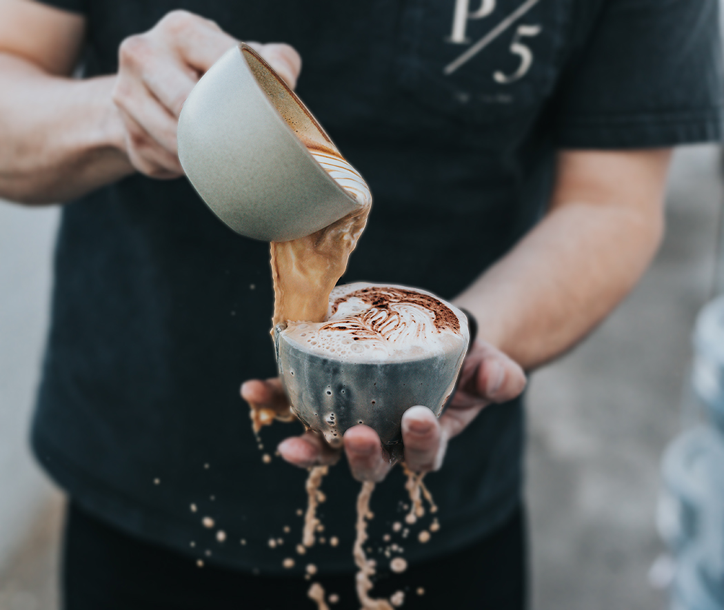 man pouring coffee from one cup into another and watching it overflow